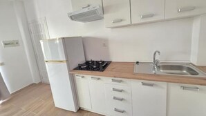 Una cocina compacta con armarios blancos, estufa integrada y un lavamanos.