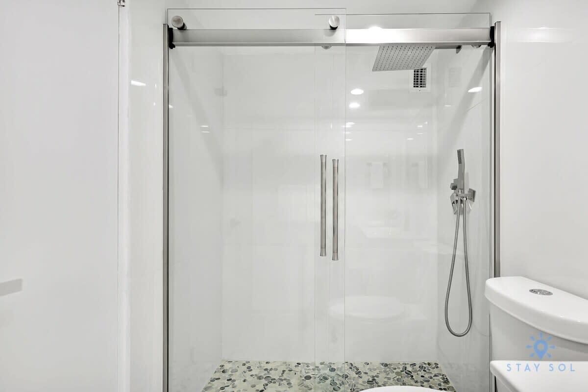 A modern bathroom with a glass-enclosed shower, a toilet, and a sink.