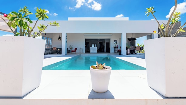 A modern house with a swimming pool in the center, surrounded by potted plants. - Charming 2-bedroom villa with AC in peaceful Grote Berg (Grote Berg)