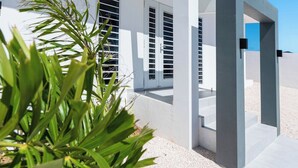 A modern building with white walls and large windows, featuring a gravel pathway and a plant in the foreground. - Charming 2-bedroom villa with AC in peaceful Grote Berg (Grote Berg)