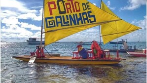A sailboat with a yellow sail and the text "Porto de Galinhas" on it, floating on calm waters. - flatportodegalinhas  (Ipojuca)