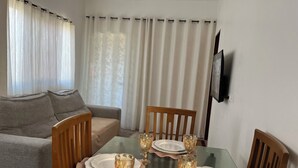 A dining area with a glass table set for four, surrounded by wooden chairs. - flatportodegalinhas  (Ipojuca)