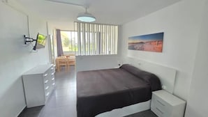 Ein modernes Schlafzimmer mit Bett, Nachttischen, einem Schreibtisch und einem Sessel.