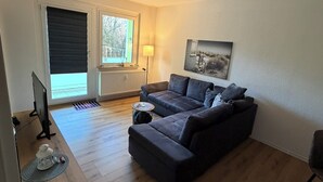 A modern living room with a sofa, a coffee table, a lamp, and a painting on the wall.