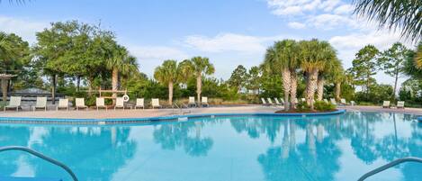 A clear blue pool surrounded by palm trees and lounge chairs.