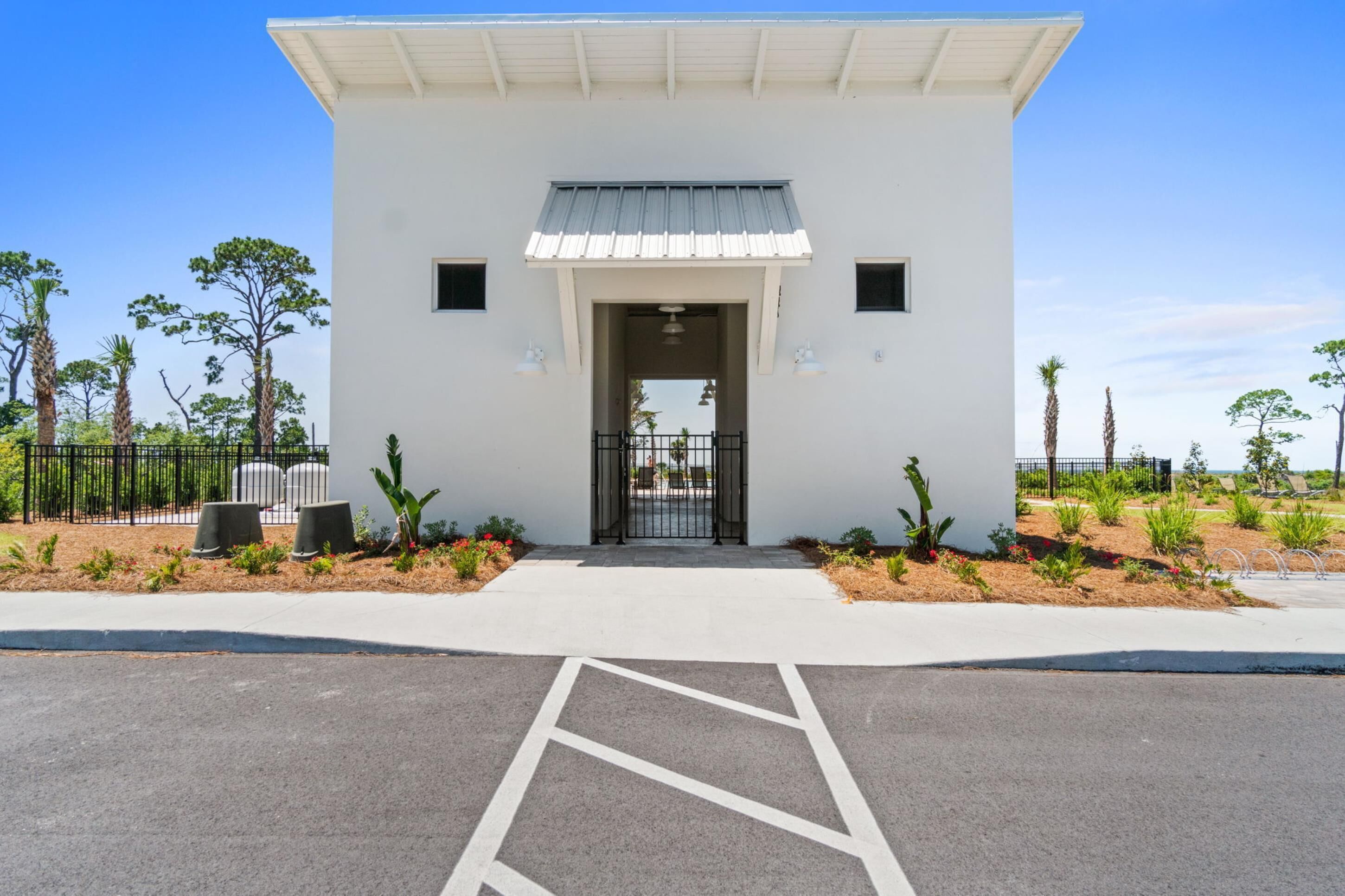 A white building with a metal roof and a gated entrance.