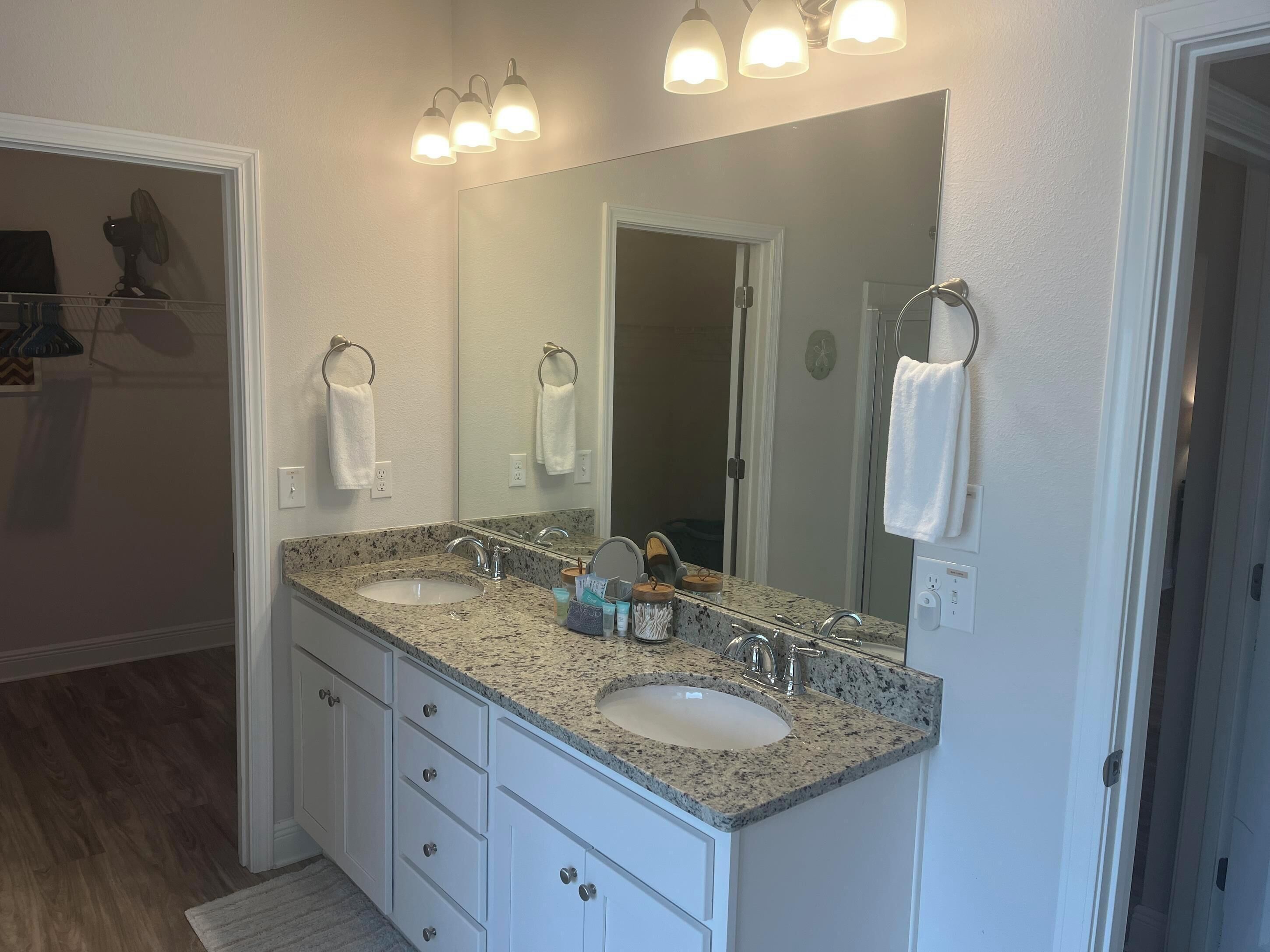 A bathroom with two sinks, a large mirror, and three wall-mounted lights.