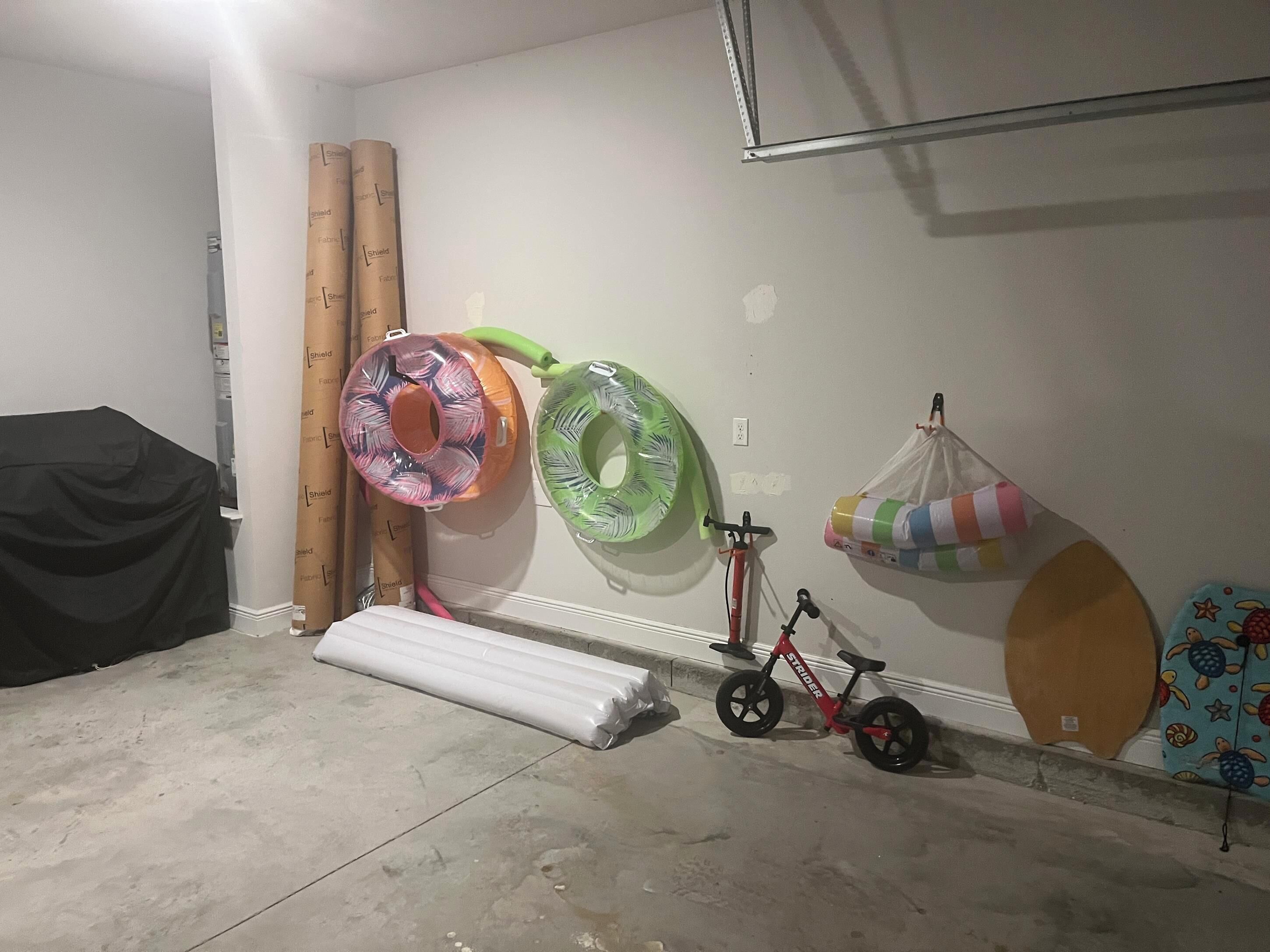 A room with a bicycle, inflatable rings, and a covered object on the floor.