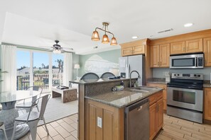 A modern kitchen with granite countertops, stainless steel appliances, wooden cabinets, and a large island. - The Great Escape is the kind of beach place you come back to. With beach access, pools, and The Deck right on site, it’s made for slow mornings, salty air, and years of memories. (Tybee Island)