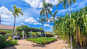 A paved pathway leading to a covered area with palm trees and a building with a tiled roof. - Villa Bon Bini Verde -Blue Bay Golf & Beach Resort (Sint Michiel)