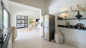 A modern kitchen with a refrigerator, a stove, and a dining area with a table and chairs. - Villa Bon Bini Verde -Blue Bay Golf & Beach Resort (Sint Michiel)