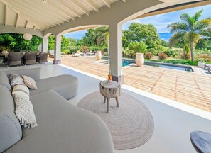 Eine moderne Außenlounge mit Pool, bequemen Sitzgelegenheiten und Blick ins umliegende Grün.