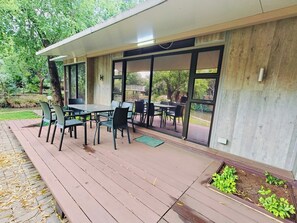 Un patio exterior con cubierta de madera, una mesa y sillas.