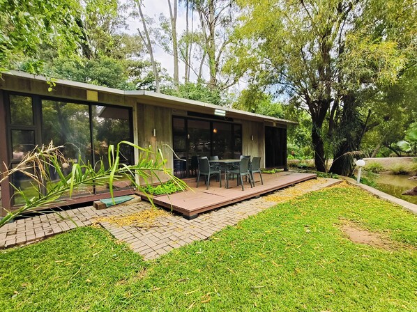Una casa moderna con patio, mobiliario exterior y un pequeño jardín.