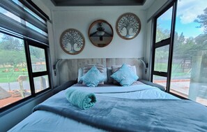 Un dormitorio con cama, ventilador de techo y tres espejos fijos en la pared.