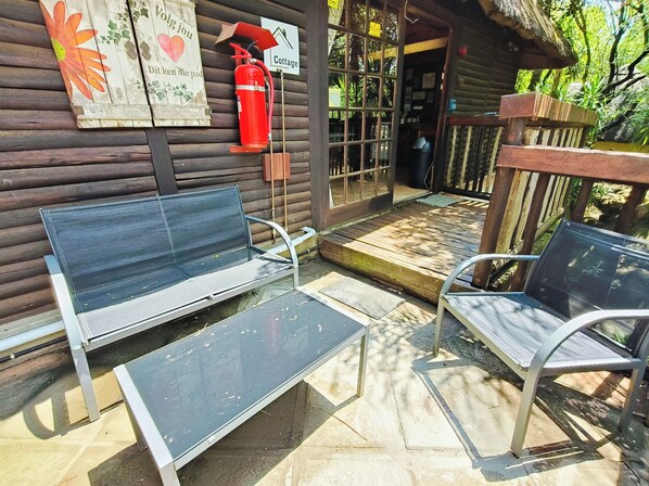 A wooden cabin with a porch, a fire extinguisher, and a bench.