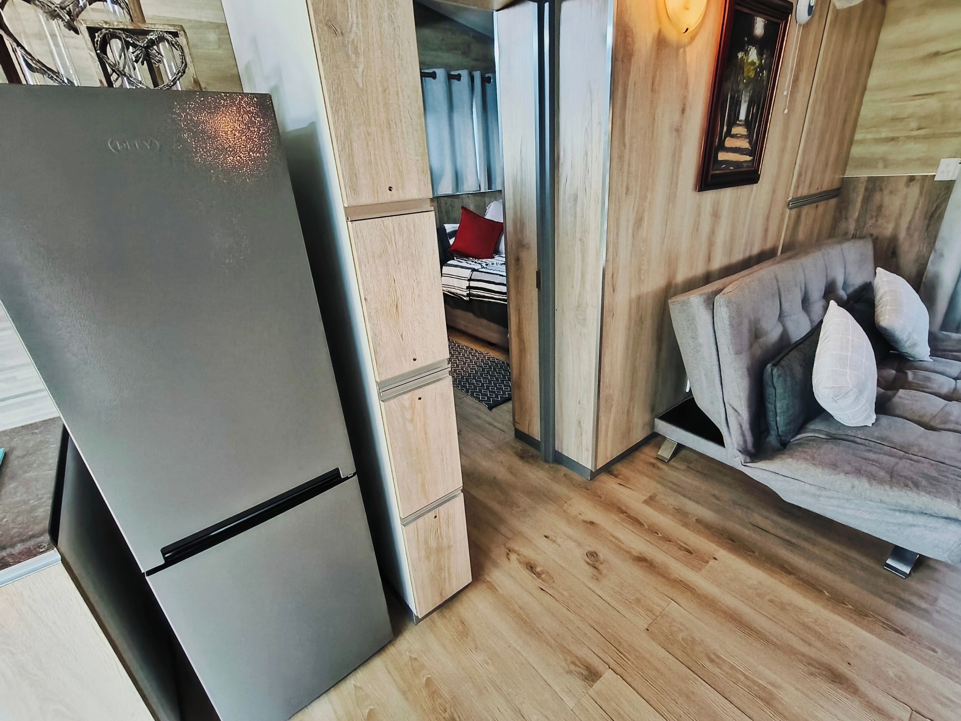 A compact living space with a modern kitchen, including a refrigerator and wooden cabinets.