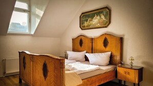 Une chambre à coucher avec un lit en bois, une table de chevet, un radiateur, une fenêtre et un tableau accroché au mur.