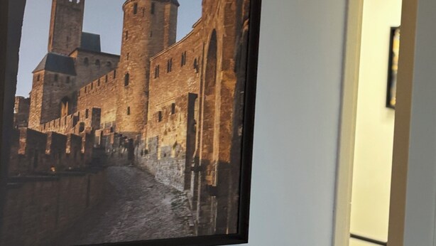 Quadre emmarcat d'un castell amb fossat, penjat a la paret.