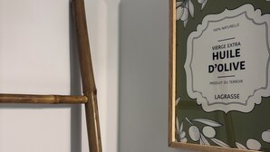 Un bany amb una barra de tovalloles de fusta, un quadre amb una imatge d'oli d'oliva i una tovallola blanca penjada a la barra.
