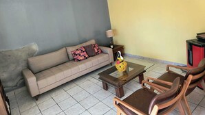 Een woonkamer met een bank, een salontafel en twee houten stoelen.