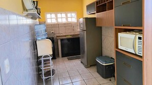 Een kleine keuken met een koelkast, magnetron en waterdispenser.