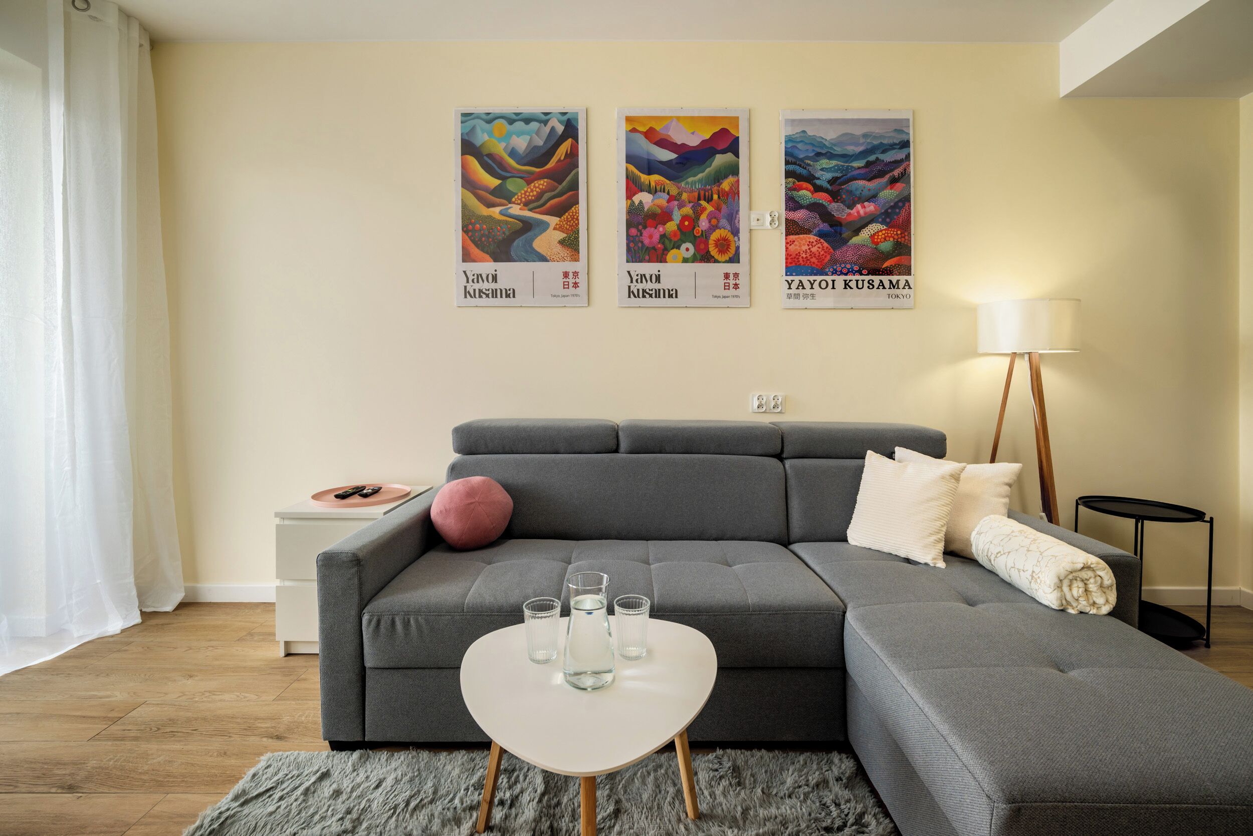 A modern living room with a grey sofa, a white coffee table, and three framed artworks on the wall.