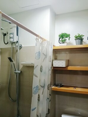 Ein Badezimmer mit Dusche, Toilette und Ablagefläche mit Topfpflanzen.