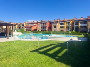 Una piscina circondata da un prato curato, con edifici a più piani sullo sfondo.