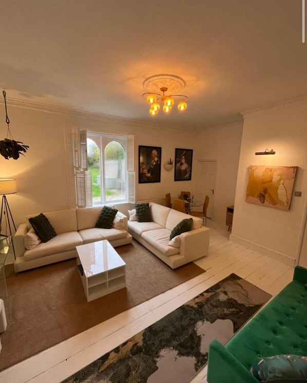 A living room with a sofa set, a coffee table, a green armchair, a floor lamp, and a ceiling light fixture. - Spacious 2 bed apartment in Addlestone (Surrey)
