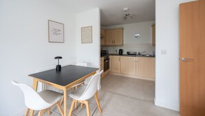 A compact kitchen with a dining area, featuring a table, chairs, and a ceiling fan. - 2 Bedroom Flat Free Parking Close to Gatwick (West Sussex)
