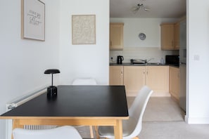 A modern kitchen with light wooden cabinets, a black countertop, and a wall-mounted clock. - 2 Bedroom Flat Free Parking Close to Gatwick (West Sussex)