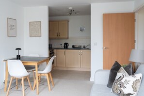 A compact living space with a dining area, kitchenette, and a sofa with decorative pillows. - 2 Bedroom Flat Free Parking Close to Gatwick (West Sussex)
