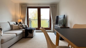 Ein Wohnzimmer mit einer Couch, einem Esstisch und einem Fernseher.