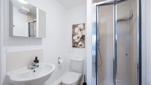 A bathroom with a white sink, toilet, and a glass-enclosed shower. - 2 Bedroom Flat Free Parking Close to Gatwick (West Sussex)