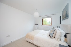 Ein Schlafzimmer mit einem Bett, einem Fenster, einer Heizung, einer Steckdose und einem Bild an der Wand.
