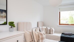 A bedroom with a bed, bedside tables, a dresser, a potted plant, and a window with a view. - 2 Bedroom Flat Free Parking Close to Gatwick (West Sussex)