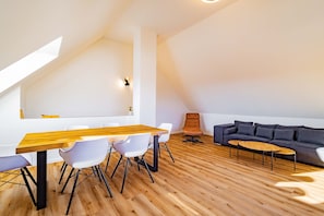 Ein modernes Loft mit Essbereich, einer Couch und Holzboden.