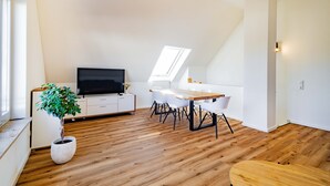 A modern loft with a dining area, a television, and a large window. - Apartment 'Kim Fewo 4' with Wi-Fi (Emmendingen)
