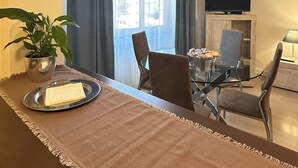 A modern dining area with a brown tablecloth, a potted plant, and a glass table. - Vatican YH (Roma)