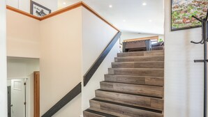 A staircase with wooden steps and a dark handrail, leading to a landing with a door and a small rug. - Fairway Front Luxury with Sweeping Mountain Views | 4BR (Mammoth Lakes)