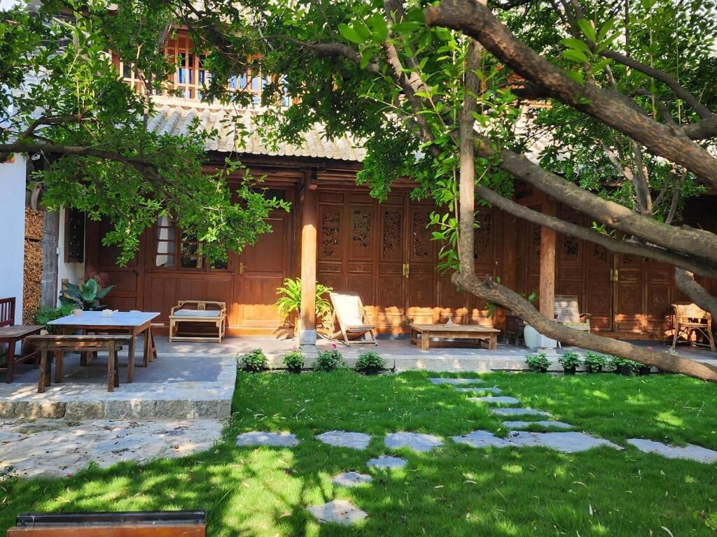 Un edificio de madera tradicional con patio jardín, escalones de piedra y mobiliario exterior.