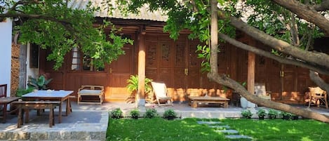 Un edificio de madera tradicional con patio jardín, escalones de piedra y mobiliario exterior.