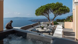 A terrace with a hot tub, seating, and a view of the sea. - Coat Of Arms Mansion (Santorini)