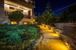 A modern building with a stone pathway leading to the entrance, surrounded by lush greenery and a metal fence. - Villa 'Zante Oliva Blu-Seaview With' with Sea View, Wi-Fi & Air Conditioning (Zakynthos Town)