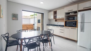 Eine moderne Küche mit Essbereich, ausgestattet mit einem runden Tisch, Stühlen, Einbau-Schränken, einer Mikrowelle und einem Kühlschrank.