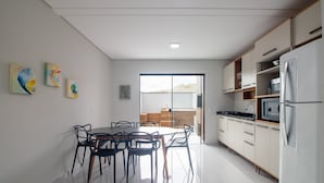 Eine moderne Küche mit Essbereich, ausgestattet mit einem großen Fenster, einem Kühlschrank und Schränken.