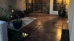 A paved patio area with potted plants and a metal gate. - Spacious 2-Bedroom Ranch Style Home in Sun Lakes Private Golf Community (Sun Lakes)