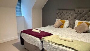 Un dormitorio con dos camas, techo inclinado y ventana con persianas.