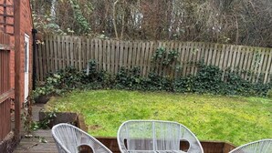 Una terraza de madera con tres sillas de mimbre blanco.